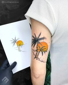 a person with a tattoo on their arm next to a piece of paper and a drawing