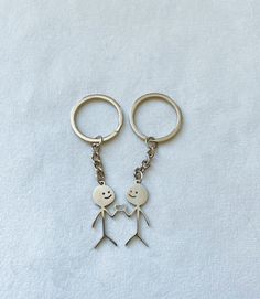 two metal key chains that have been shaped to look like people holding each other's hands