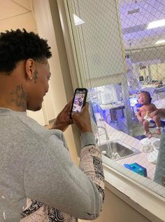 a woman looking at her cell phone while standing in front of a window