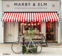 a bicycle parked in front of a store with red and white striped awnings