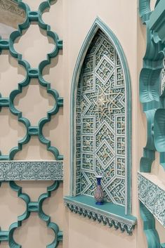 an intricately designed window in the middle of a room with blue and white walls