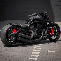 a black motorcycle parked in front of a building on a brick road with red lights