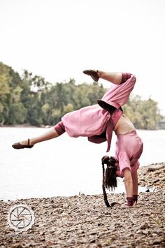 a woman is doing a handstand on the beach by the water's edge