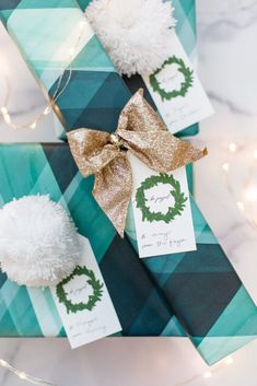 two presents wrapped in green and gold paper with pom - poms on them