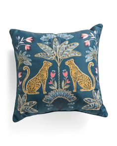 a blue pillow with gold leopards and flowers on the front, sitting against a white background