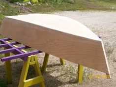 a wooden boat sitting on top of a purple and yellow bench