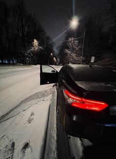 a car parked on the side of a snowy road at night