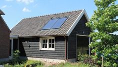 a small black house with a solar panel on the roof and two windows in front