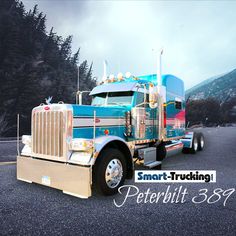 a blue semi truck parked in a parking lot next to some pine trees and mountains