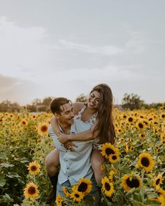 a man and woman hugging in the middle of a sunflower field with one another