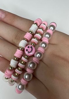 a woman's hand holding three bracelets with pink and white beads