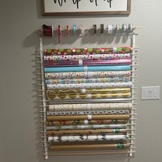 a wall mounted craft supply rack holding many different types of fabric