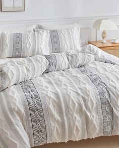 a bed with white and black striped comforter in a room next to a nightstand