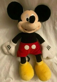 a mickey mouse stuffed animal sitting on top of a white sheet