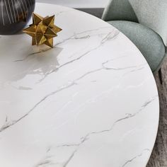 a white marble table with gold star decorations on it's top and two chairs in the background