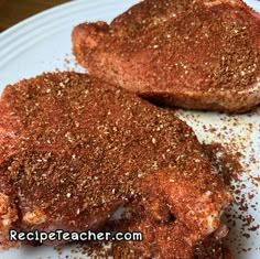 two pieces of meat on a plate with seasoning