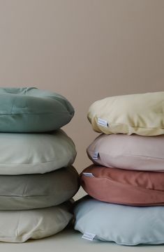 four pillows stacked on top of each other in different colors and sizes, with one pillow folded up to the side