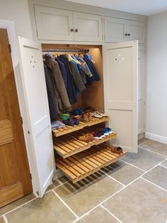 an open closet with clothes and shoes on shelves next to a white door in a room