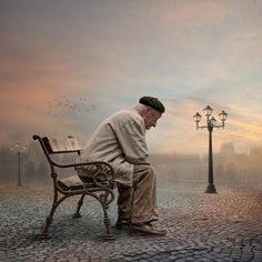 a man sitting on top of a bench next to a lamp post