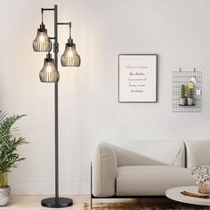 a living room with a white couch and three lights on the floor next to a potted plant