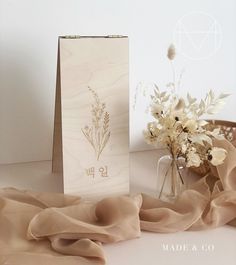 a vase filled with flowers on top of a table next to a card and paper bag