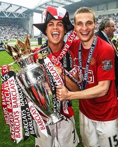 two soccer players are holding the trophy in front of their faces and smiling at the camera