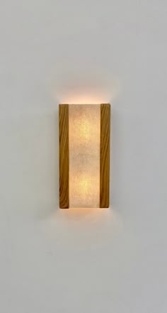 a wooden wall light mounted on the side of a white wall with a square shade