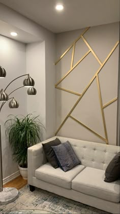 a living room with a white couch and some lights on the wall next to a potted plant