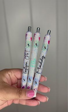 three pens with writing on them are held in the palm of a woman's hand