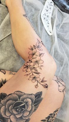 a woman's legs with tattoos on them and flowers in the middle of her leg