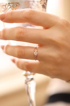 a woman's hand holding a wine glass with a diamond ring on top of it