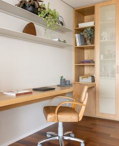 an office chair sitting in front of a desk with bookshelves and plants on it