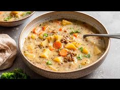 two bowls filled with soup on top of a table next to some bread and vegetables