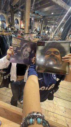 a person holding up a magazine with a man's face on it in front of a mirror