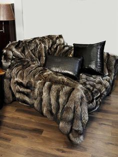 a fur couch with pillows on top of it and a lamp in the corner next to it