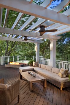 an outdoor living area with couches, tables and fire pit on the decking