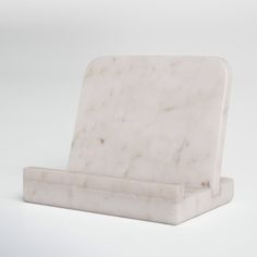 a white marble book holder on a plain surface with one section folded up to the side