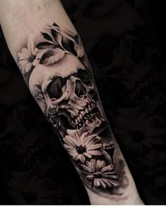 a skull and flowers tattoo on the left arm, with black and white ink in it