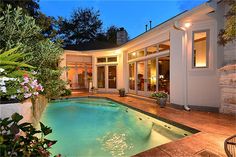 an outdoor swimming pool surrounded by greenery and flowers at night with the lights on