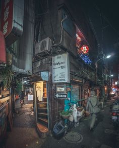 a man walking down the street in front of a store at night with neon signs