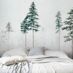 a bed with white sheets and pillows in front of a forest wall mural