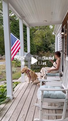 a woman sitting on a porch next to a dog and rocking chairs with the american flag in the background