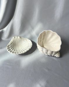 two shell shaped dishes sitting on top of a white sheet