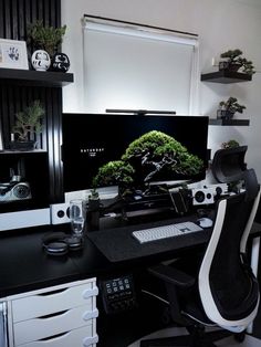 a desk with a computer monitor, keyboard and plant on it in front of a window