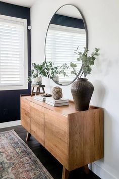 a large round mirror on the wall above a wooden dresser