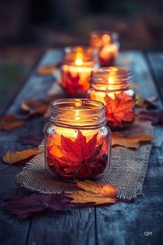 candles are lit with autumn leaves on the table