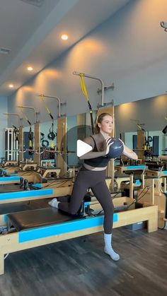 a woman is doing an exercise on a machine in a gym with other machines behind her