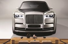 a silver rolls royce parked in front of a wooden table