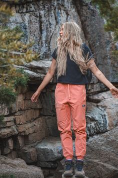 a woman standing on top of a rock formation with her arms spread out to the side