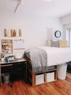 a bedroom with a bed, desk and storage bins on the floor in front of a window